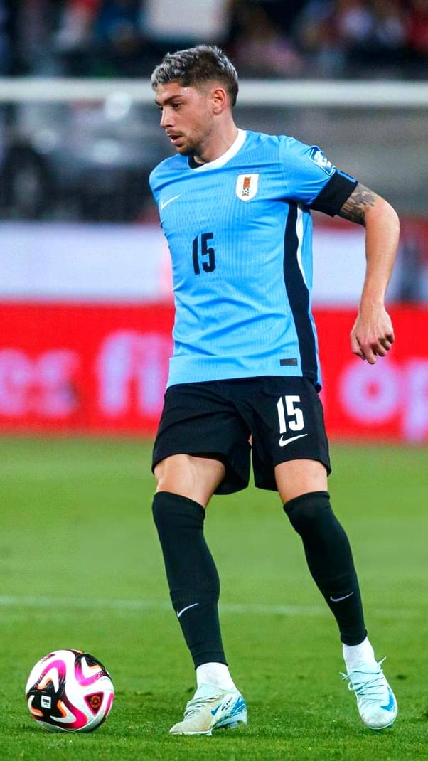 A soccer player in a light blue jersey with the number 15 controls a ball on the field during a match, as fans enjoy the live action through Colombia IPTV.