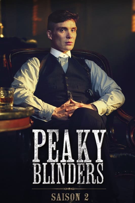 A man in a suit sits in a leather chair with hands clasped. Peaky Blinders and Saison 2 are written at the bottom, hinting at the gripping drama that can be streamed on Colombia IPTV. The scene is dimly lit, giving a serious, dramatic mood.